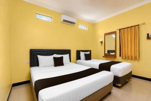 two beds in a room with yellow walls at Hotel O near Alun-Alun Kidul formerly Ndalem Mantrijeron Hotel in Yogyakarta