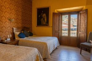 a hotel room with two beds and a balcony at Hotel Casa Santa Lucia in Zacatecas