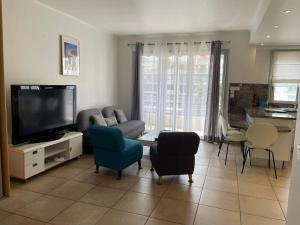 a living room with a couch and a tv and chairs at Palais Rouaze in Cannes
