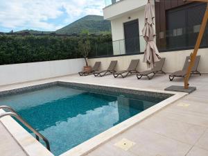 a swimming pool with chairs and an umbrella at Symphony Tivat Apartment in Donja Lastva