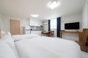 a bedroom with a white bed and a kitchen at Y2 Stay Hotel in Sokcho