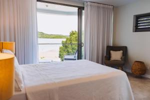 a bedroom with a bed and a window and a chair at 201 - Ocean Views Oceanfront Large Balcony in Suva