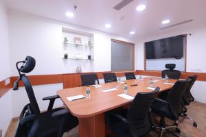 a conference room with a large wooden table and chairs at Savoy Suites Noida in Noida +32 photos