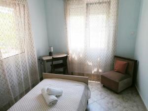 a bedroom with a bed and a chair and a window at Blue Marianthi in Ávdhira