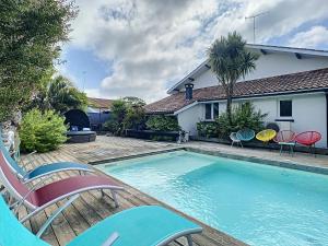 a swimming pool with chairs and a house at Villa Dedele in Soustons