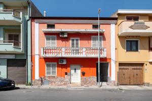 an orange building with a balcony on a street at Bikers Rooms in Sestu