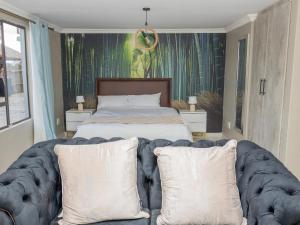 a bedroom with a bed and a couch with pillows at Tlatso lifestyle and Accommodation in Hammanskraal Station +9 photos