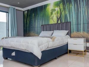 a bedroom with a blue bed with a painting on the wall at Tlatso lifestyle and Accommodation in Hammanskraal Station
