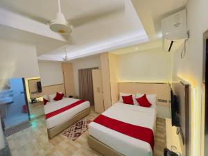 a hotel room with two beds and a television at Arham Beach Resort in Cox's Bazar