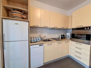 a kitchen with white cabinets and a refrigerator at Cosy Garden Flat, Beach, Pool in Plépi