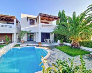 a villa with a swimming pool in front of a house at Cosy Garden Flat, Beach, Pool in Plépi