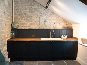 a kitchen with a sink and a brick wall at The Farmhouse in Langport +44 photos