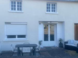 a table and chairs in front of a white house at Maison de campagne in Clessé