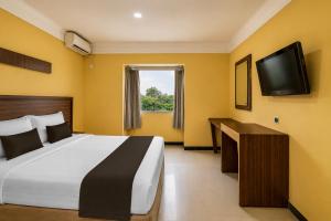 a hotel room with a bed and a television at Hotel O near RSUD Arifin Achmad formerly Damon Butik Hotel in Limbangan