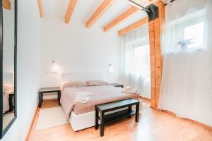 a white bedroom with a bed and two tables at Affitta camere LUNAR in Borgo