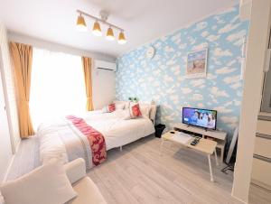 a bedroom with a bed and a desk with a television at Maison New River B-203 in Chiharachō