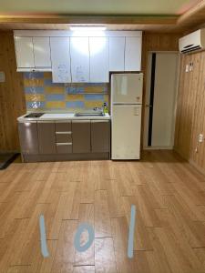 an empty kitchen with a refrigerator and a wooden floor at 신화펜션 in Koryŏng