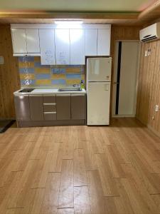 a kitchen with a white refrigerator and a wooden floor at 신화펜션 in Koryŏng