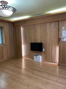 a room with wooden walls and a flat screen tv at 신화펜션 in Koryŏng +13 photos
