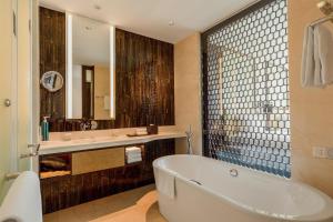 a bathroom with a tub and a sink and a mirror at Hilton Da Nang in Danang