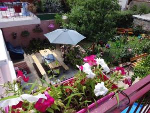 a garden with a table and an umbrella and flowers at Art House Old Town in Podgorica