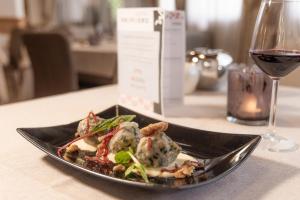 a plate of food on a table with a glass of wine at Hotel Primiero in Tonadico