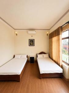 two beds in a room with a window at Nhà nghỉ Hoa Ngàn Tam Đảo in Tam Ðảo