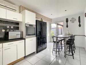 a kitchen with white cabinets and a table with chairs at Villa Dedele in Soustons