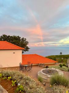 an orange roofed patio with a table and chairs at Casas do Pargo - Casa B Palheiro in Ponta do Pargo