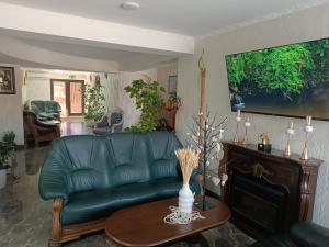 a living room with a green leather couch and a table at Hotel Racu Family in Komrat