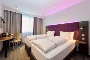 a hotel room with two beds and a desk at Premier Inn Koblenz City in Koblenz