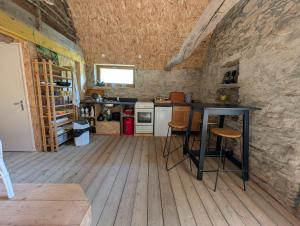 a kitchen with a black table in a stone wall at Cabane du Serris - Expérience insolite dans les Pyrénées in Beaudéan
