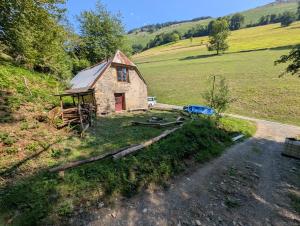 a small stone house in a field with a road at Cabane du Serris - Expérience insolite dans les Pyrénées in Beaudéan