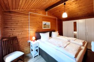 a bedroom with a large bed in a wooden wall at Ferienbungalow Seeluft in Loddin