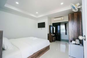 a white bedroom with a bed and a tv at โรงแรมคุณหญิงโฮเตล in Nan