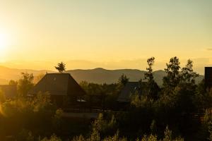 a view of a house with the sunset in the background at Casa de Lângă Mesteceni in Dealu Negru
