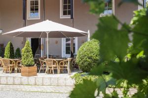 eine Terrasse mit Tischen, Stühlen und einem Sonnenschirm in der Unterkunft Vila Belaggio in Plattling