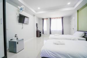 a white room with two beds and a tv at โรงแรมคุณหญิงโฮเตล in Nan +4 photos