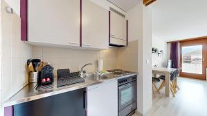 a kitchen with white cabinets and a sink and a table at Bright studio in Saillon, a few steps from Les Bains in Saillon