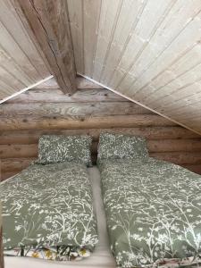 a bed and pillows in a wooden room at Miško sodyba in Gedvainiai