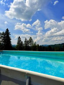 Ein Schwimmbad unter blauem Himmel und Wolken in der Unterkunft LUCE Chata in Nieledwia