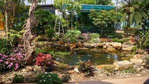 a garden with a pond and flowers in front of a building at Cổ Thiên Thạch Kiếm in Ðại Lào