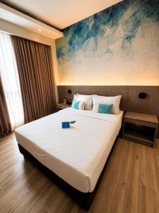 a bedroom with a large white bed with a painting on the wall at The Litton Hotel by Carterson in Naga