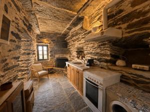 a kitchen with a stove top oven in a stone wall at Nostos Kea in Káto Meriá
