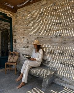 a woman sitting on a bench reading a book at Nostos Kea in Káto Meriá