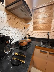 a kitchen with a stove top with two wine glasses at Pedro suite by iconic apartment in Lagos