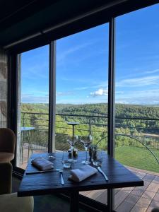 a wooden table with wine glasses on a balcony at Le Panoramic Garabit in Anglards-de-Saint-Flour