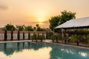 a swimming pool with a sunset in the background at Aangan Resort Mandawa in Mandāwa