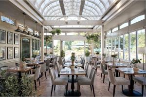 a dining room with tables and chairs and windows at Rhinefield House Hotel in Brockenhurst