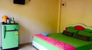 a bedroom with a green bed and a refrigerator at MAIYOK in Ko Si Chang